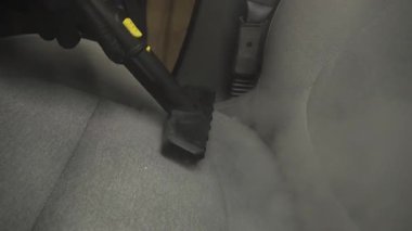 Otomobil 4K videosunu dezenfekte etmek ve temizlemek için buhar makinesini kullanarak arabadaki koltukları buharla temizliyor. Buharlı araç koltuklarının ayrıntıları temiz.