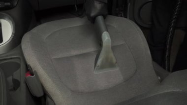 Elektrikli süpürgeyle arabanın arka koltuğunu süpürmek. Özel süpürge başlığıyla otomatik koltuklar detaylandırılıyor.