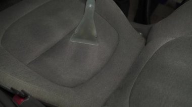 Elektrikli süpürgeyle arabanın arka koltuğunu süpürmek. Özel süpürge başlığıyla otomatik koltuklar detaylandırılıyor.