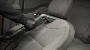 Elektrikli süpürgeyle arabanın arka koltuğunu süpürmek. Özel süpürge başlığıyla otomatik koltuklar detaylandırılıyor.