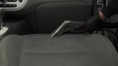 Elektrikli süpürgeyle arabanın arka koltuğunu süpürmek. Özel süpürge başlığıyla otomatik koltuklar detaylandırılıyor.