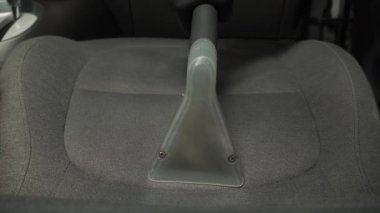 Elektrikli süpürgeyle arabanın arka koltuğunu süpürmek. Özel süpürge başlığıyla otomatik koltuklar detaylandırılıyor.