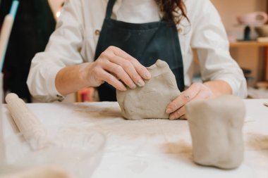 Potter seramik ürünleri için ıslak kil heykeli yapıyor. Çömlek atölyesindeki masaya seramik kil ürünü yapan bir kadın çömlekçinin elleri.