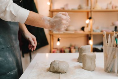 Dişi çömlekçi heykel yapmadan önce bir parça kil sarar. Seramik çanak çömlek yapmak için kil hazırlanıyor