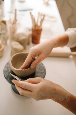 Sanatçı kadın çömlekçi çarkında kilden bir kase yapıyor. Atölyede seramik çanak çömlek oluşturma