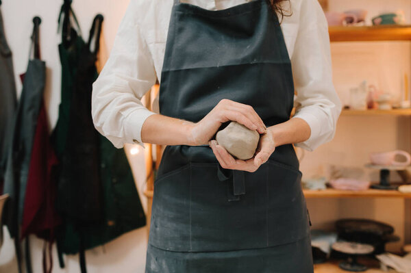 Woman potter works with wet clay in the pottery studio. Girl potter is creating a ceramic ware in the workshop