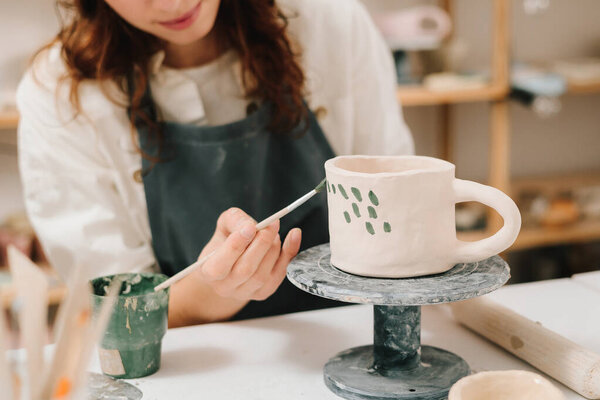 Процесс проектирования кубка с традиционным узором в мастерской керамики. Ремесленные марки декоративные символы на сухой глине чаши