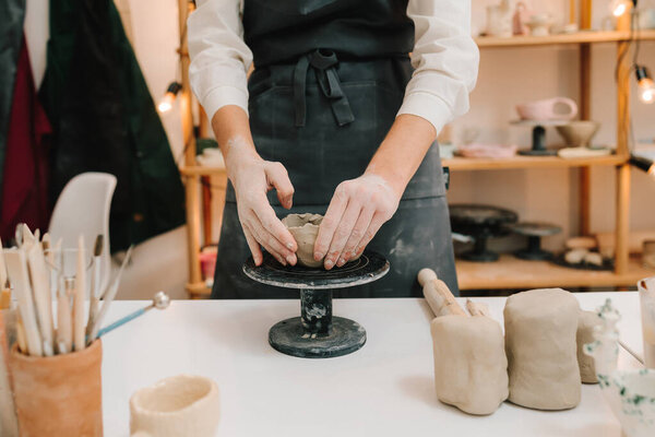 Руки превращают глину в тарелку в мастерской крупным планом. Ремесленные скульптуры керамической чаши с помощью гончарного круга