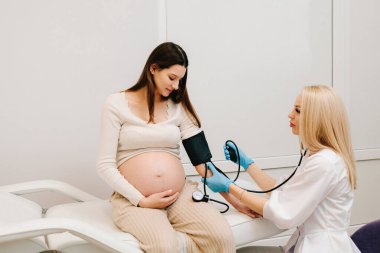 Hamilelik sırasında yüksek basınç sorunu. Jinekolog, doğum merkezinde hamile bir hasta için kan basıncını ölçer.