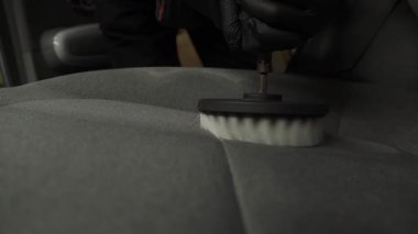 4K kuru temizleme videosu için tekstil koltuğuna deterjan sürüyorum. Araba tekstil koltuklarına deterjan sürmek kuru temizleme için fırçayla delmek.