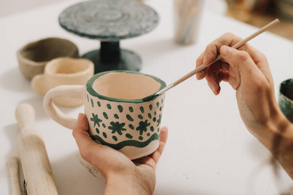Дизайн глиняной чашки с традиционным узором. Художник делает украшения на глиняной керамической кружке после обжига печи