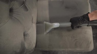 Temizlikçi, deterjan 4k video ile temizleme makinesi kullanarak kanepeyi temizliyor. Döşeme mobilyalarının tozunu ve lekelerini temizlemek için sökücü kullanıyor..