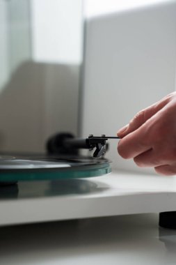 Müzik aşığı, vinil turntable 'da vinil retro müzik çalmadan önce tonkolunu elinde tutuyor. Müzisyen, tonkollarını vinil turntable 'a ayarlıyor.