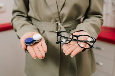 Optik merkezde gözlük ve yeniden kullanılabilir lens seçimi. Göz sağlığı yerinde olan bir kadın gözlük ve lens arasında seçim yapar.