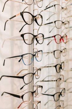 Görme düzeltmesi. Optik dükkanında farklı çerçeveli gözlükler. Müşteri, raftan temiz lensli gözlük seçiyor.