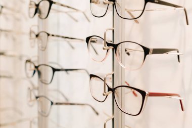 Görme düzeltmesi. Optik dükkanında farklı çerçeveli gözlükler. Müşteri, raftan temiz lensli gözlük seçiyor.