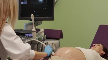 Hastanenin 4K videosunda ultrasonda hamile bir kadın var. Ultrason cihazıyla hamilelik sağlık kontrolü.