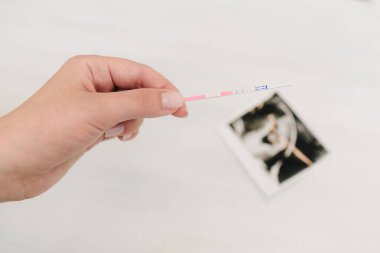Pozitif hamilelik testi ve beyaz arka planda bir bebeğin sonogram fotoğrafı. Müstakbel annenin hamilelik testi pozitif sonuç veriyor.