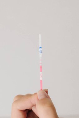 Beyaz arka planda pozitif hamilelik testi. Müstakbel annenin hamilelik testi pozitif sonuç veriyor.