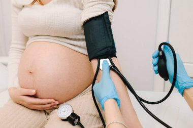 Hamilelik sırasında yüksek basınç sorunu. Jinekolog, doğum merkezinde hamile bir hasta için kan basıncını ölçer.