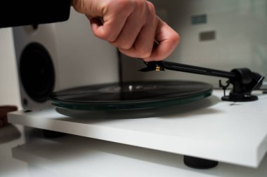 Müzik aşığı, vinil turntable 'da vinil retro müzik çalmadan önce tonkolunu elinde tutuyor. Müzisyen, tonkollarını vinil turntable 'a ayarlıyor.