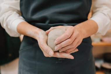 Çömlekçi kız atölyede seramik bir alet yapıyor. Çömlekçi kadın çömlek atölyesinde ıslak kille çalışıyor.