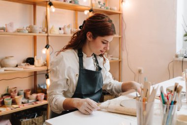 Kadın zanaatkar gelecekteki seramik tabaklar için çemberleri ölçer. Çömlek çarkını kalıba dökmeden önce kilin hazırlanması
