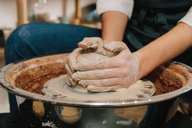 Çömlek atölyesindeki dönen çarkın üzerinde seramik toprak malzemesi yapma süreci. Zanaatkar çömlek çarkına ıslak bir kil kalıbı koyar.
