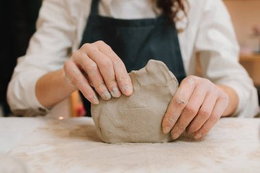 Çömlek atölyesindeki masaya seramik kil ürünü yapan bir kadın çömlekçinin elleri. Potter seramik ürünleri için ıslak kil heykeli yapıyor.