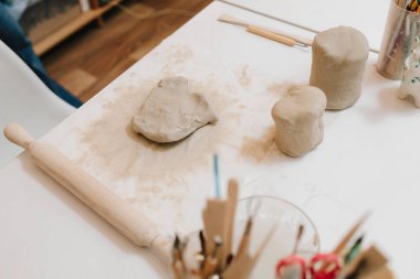 Çömlek atölyesindeki masaya seramik kil ürünü yapan bir kadın çömlekçinin elleri. Potter seramik ürünleri için ıslak kil heykeli yapıyor.