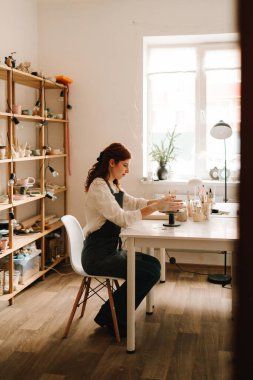 Atölyede seramik çanak çömlek yapmak. Sanatçı kadın çömlekçi çarkında kilden bir kase yapıyor.