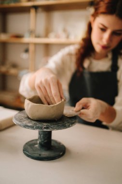 Atölyede seramik çanak çömlek yapmak. Sanatçı kadın çömlekçi çarkında kilden bir kase yapıyor.