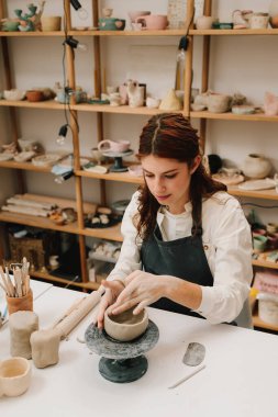 Atölyede seramik çanak çömlek yapmak. Sanatçı kadın çömlekçi çarkında kilden bir kase yapıyor.