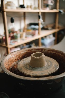 Potter çömlek atölyesinde kilden seramik bir kupa yontuyor. Çömlekçi araçlarıyla toprak kalıbı oluşturuluyor