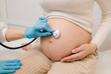 Hamilelik kontrolü. Jinekolog ve steteskoplu bir jinekolog jinekoloji kliniğindeki randevuda bebeğin kalp atışlarını dinliyor.