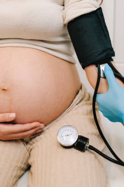 Hamilelik sırasında yüksek basınç sorunu. Jinekolog, doğum merkezinde hamile bir hasta için kan basıncını ölçer.