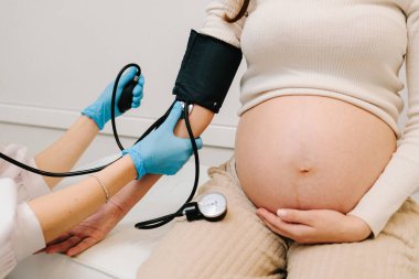 Hamilelik sırasında yüksek basınç sorunu. Jinekolog, doğum merkezinde hamile bir hasta için kan basıncını ölçer.