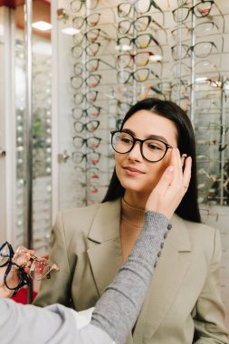 Oftalmolog optik dükkandaki kadın hastalar için gözlük seçiyor. Oftalmolog randevusunda şeffaf lensli gözlük seçmek