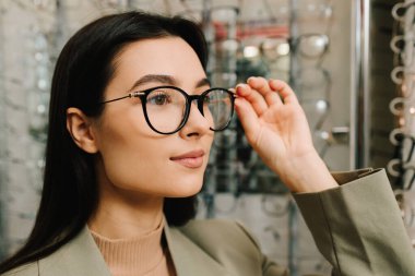 Görme düzeltmesi. Optik dükkanında farklı çerçeveli gözlükler. Müşteri, raftan temiz lensli gözlük seçiyor.