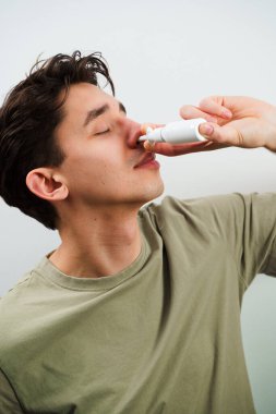 Adam tedavi için burun spreyi kullanıyor. Hasta adam evde akan burundan kurtulmak için burun damlası enjekte ediyor.