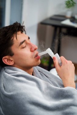 Evde nebulizatörün yardımıyla ağız solunumu. Hasta adam evde grip tedavisi için ağız spreyi nebulizatörü kullanıyor.