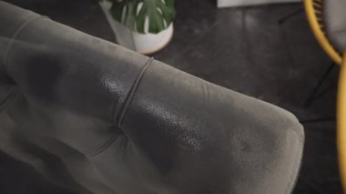 Kuru temizleme için kanepeye deterjan sıkmak 4K ekstraktör videosu kullanmak. Evdeki koltuktan lekeleri ve kiri çıkarmak için kuru temizleme işlemi. Profesyonel temizlik servisi..