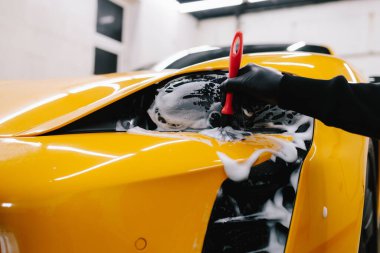 Araba farlarını köpük ve yumuşak fırçayla temizliyorum. Spor araba farlarını temizleme işlemi. Sabun köpüğü ve fırçayla yıkayın.