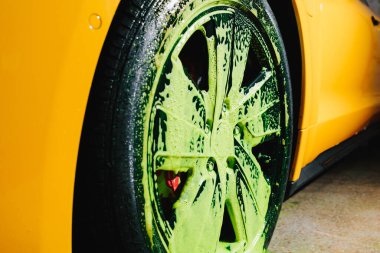 Araba yıkamada yeşil sabunla tekerlek temizleme işlemi. Adam serviste araba tamiri için yeşil sabun solüsyonu kullanıyor.