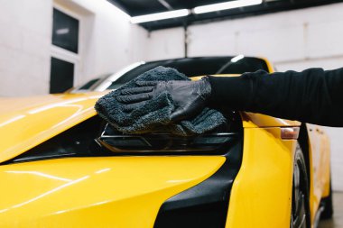 Mikrofiber silme ve araba farı cilası için balmumu sıvısı kullanma. Serviste mikrofiber bezle far parlatma işlemi spor araba detaylandırması
