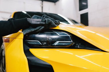 Mikrofiber silme ve araba farı cilası için balmumu sıvısı kullanma. Serviste mikrofiber bezle far parlatma işlemi spor araba detaylandırması