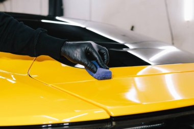 Otomobil servisinde sünger yakın çekim kullanılarak araba üzerindeki seramik katmanın uygulanması. Arabayı çiziklerden korumak için nano seramik koruyucu palto.