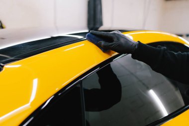 Araba servisi çalışanı spor araba gövdesine seramik kaplama uyguluyor. Detaylandırma servisinde seramik kaplama prosedürü.