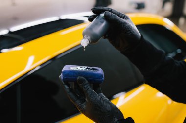 Arabaya koruyucu bir nano katman uygulamak için şişeden süngere seramik sıvı dökme işlemi. Ayrıntılı hizmet çalışanı sünger yakın çekim seramik koruyucu sıvı uygular