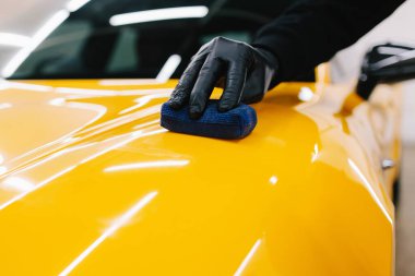 Sarı spor araba için koruyucu nano katman oluşturmak için seramik sıvıyı karıştırmak. Ayrıntılı hizmet çalışanı spor arabaya seramik koruyucu sıvı uygular
